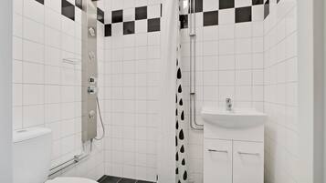 A bathroom with a toilet, shower, and sink.
