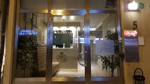 The entrance to Hotel Kringelstaden with a reception desk, a sign indicating reception hours, and a plant outside. - Hotell Kringelstaden (Sodertalje)