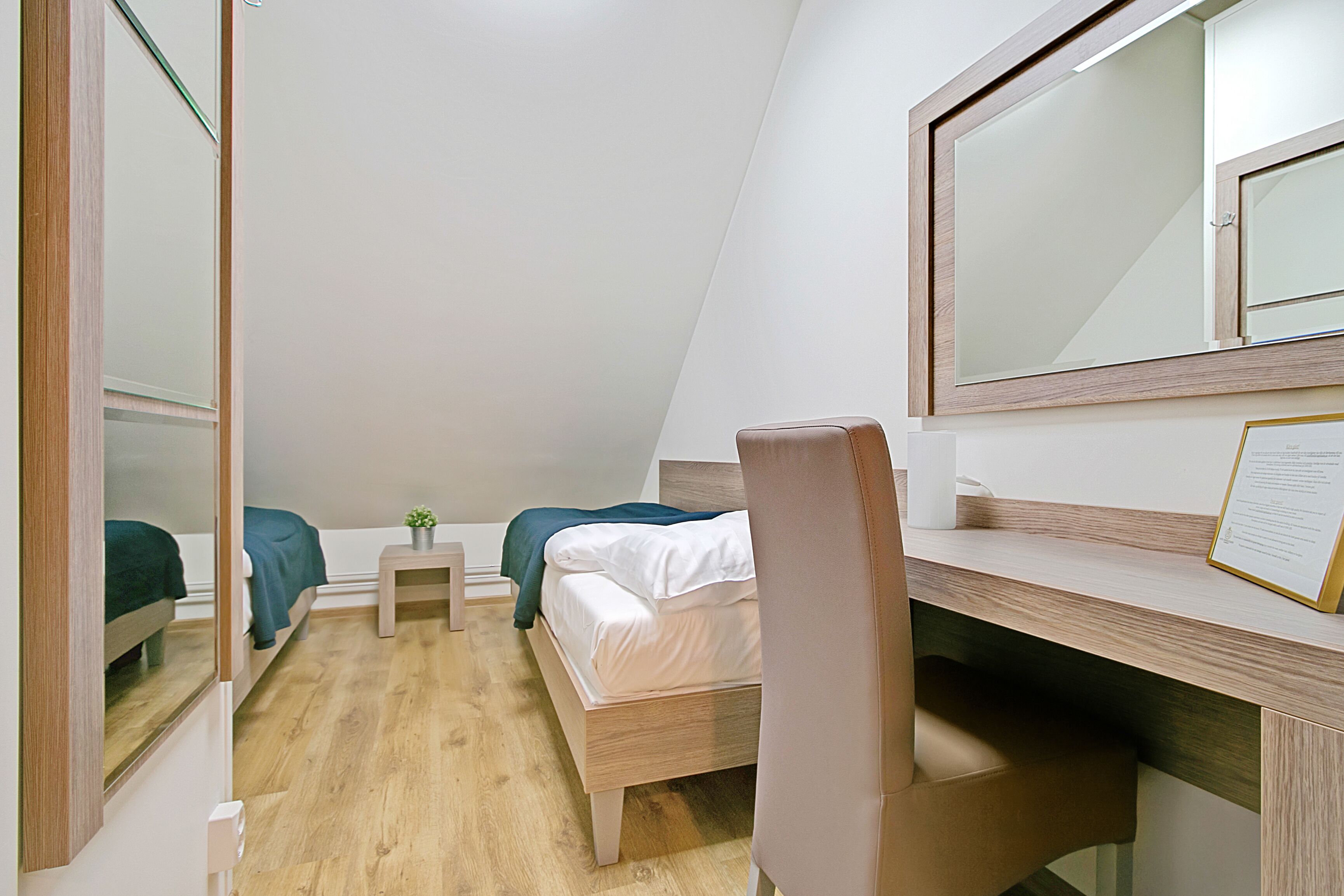 Un dormitorio moderno y funcional con dos camas individuales, un escritorio y una silla.