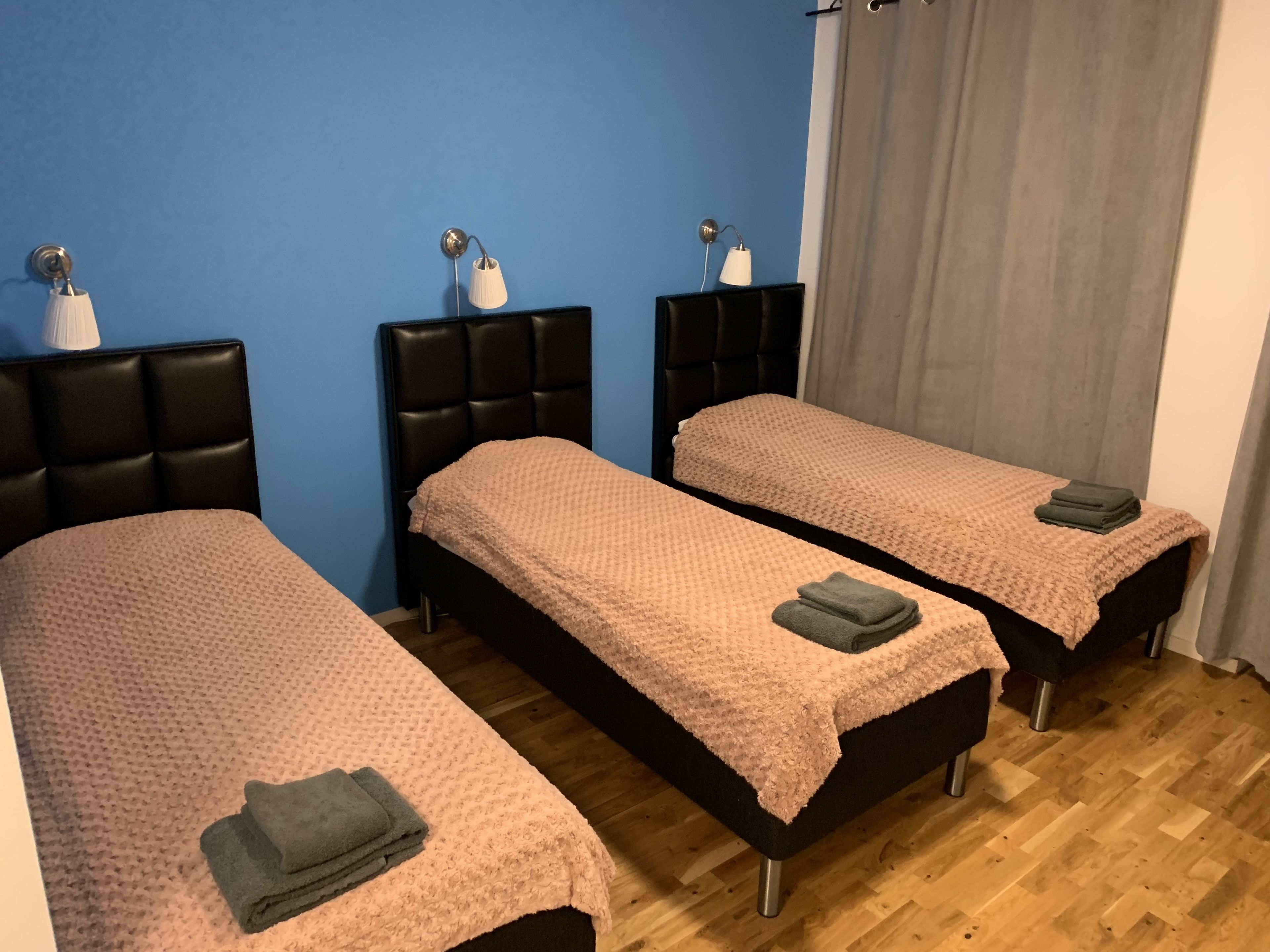 A room with two beds, each with a headboard and a bedside table.