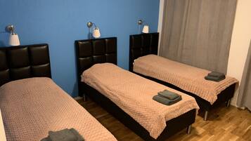 A room with two beds, each with a headboard and a bedside table.