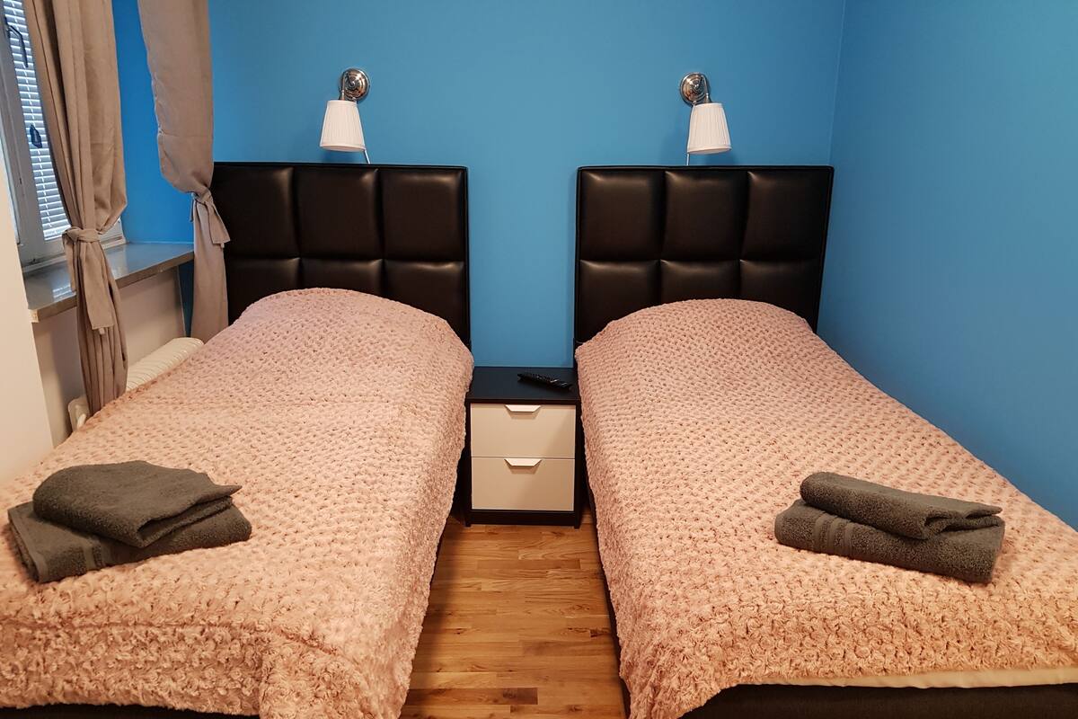 Ein Zweibettzimmer mit zwei Betten, jeweils mit Kopfteil und Nachttisch.