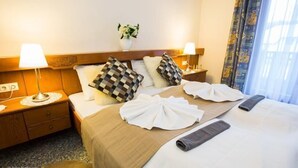 A hotel room with a neatly made bed, checkered pillows, a bedside lamp, and a small plant on the nightstand. - Hotel Seelacherhof (Sankt Kanzian am Klopeiner See)