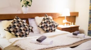 A neatly made bed with checkered pillows, a wooden headboard, and a bedside table with a lamp.