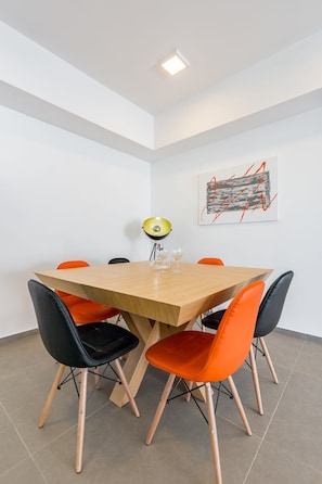 Ein Konferenzraum mit Holztisch, orangefarbenen und schwarzen Stühlen, einer Schreibtischlampe und einem Bilderrahmen mit einem abstrakten Gemälde an der Wand.