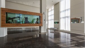 Un vestíbulo amplio con un gran acuario, muebles modernos y ventanas grandes que dejan entrar luz natural.