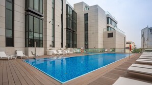 A modern building with a rooftop pool, white lounge chairs, and a clear blue pool. - White City Tower (Tel Aviv)