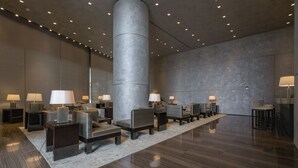 A modern lobby with a central column, multiple seating areas, and tables with lamps. - White City Tower (Tel Aviv)