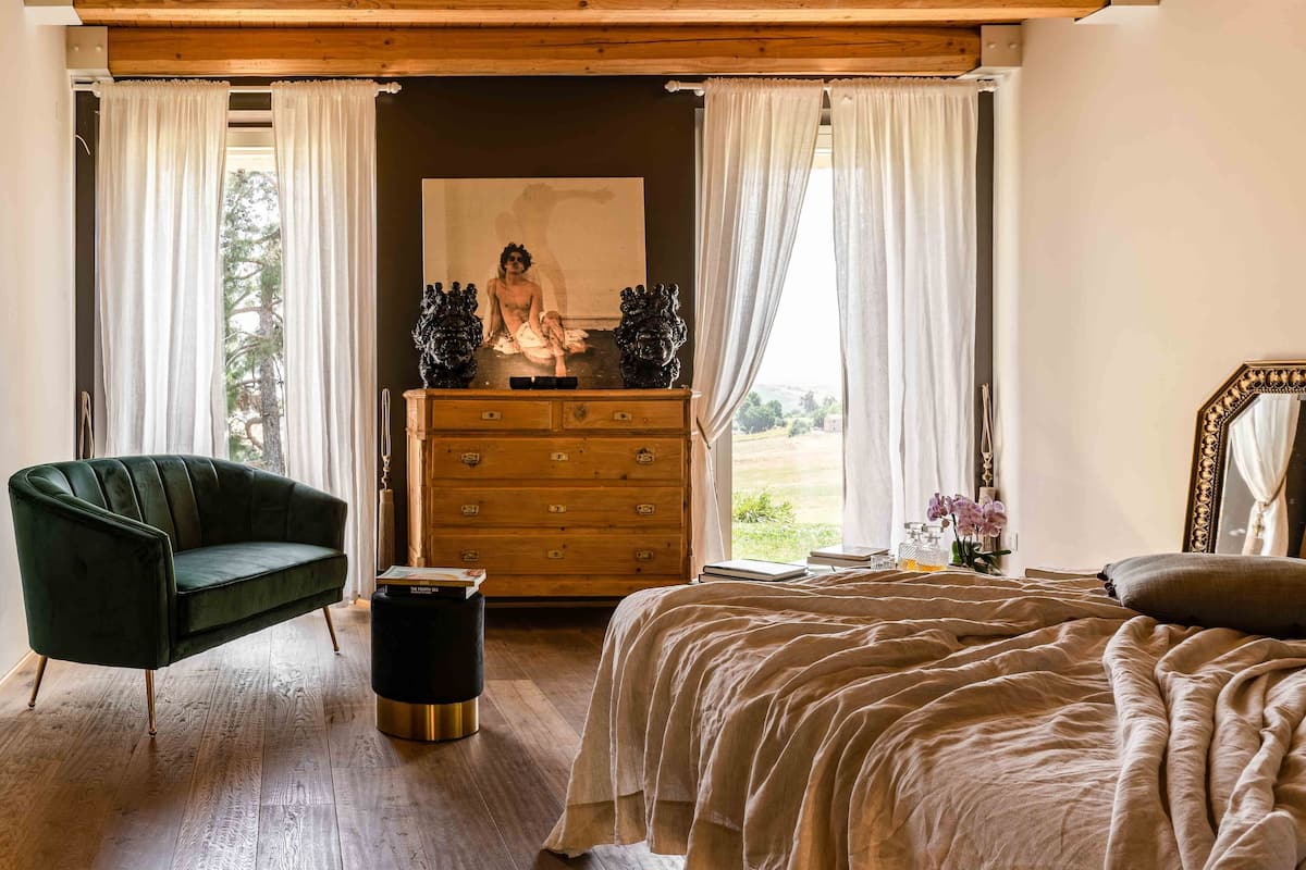 Une chambre à coucher avec un lit, une commode, une chaise et un tableau accroché au mur.