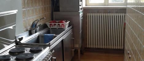 Cocina compacta con estufa a gas, un lavamanos y un ventanal que proporciona luz natural.