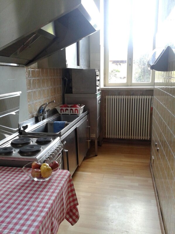 Cocina compacta con estufa a gas, un lavamanos y un ventanal que proporciona luz natural.