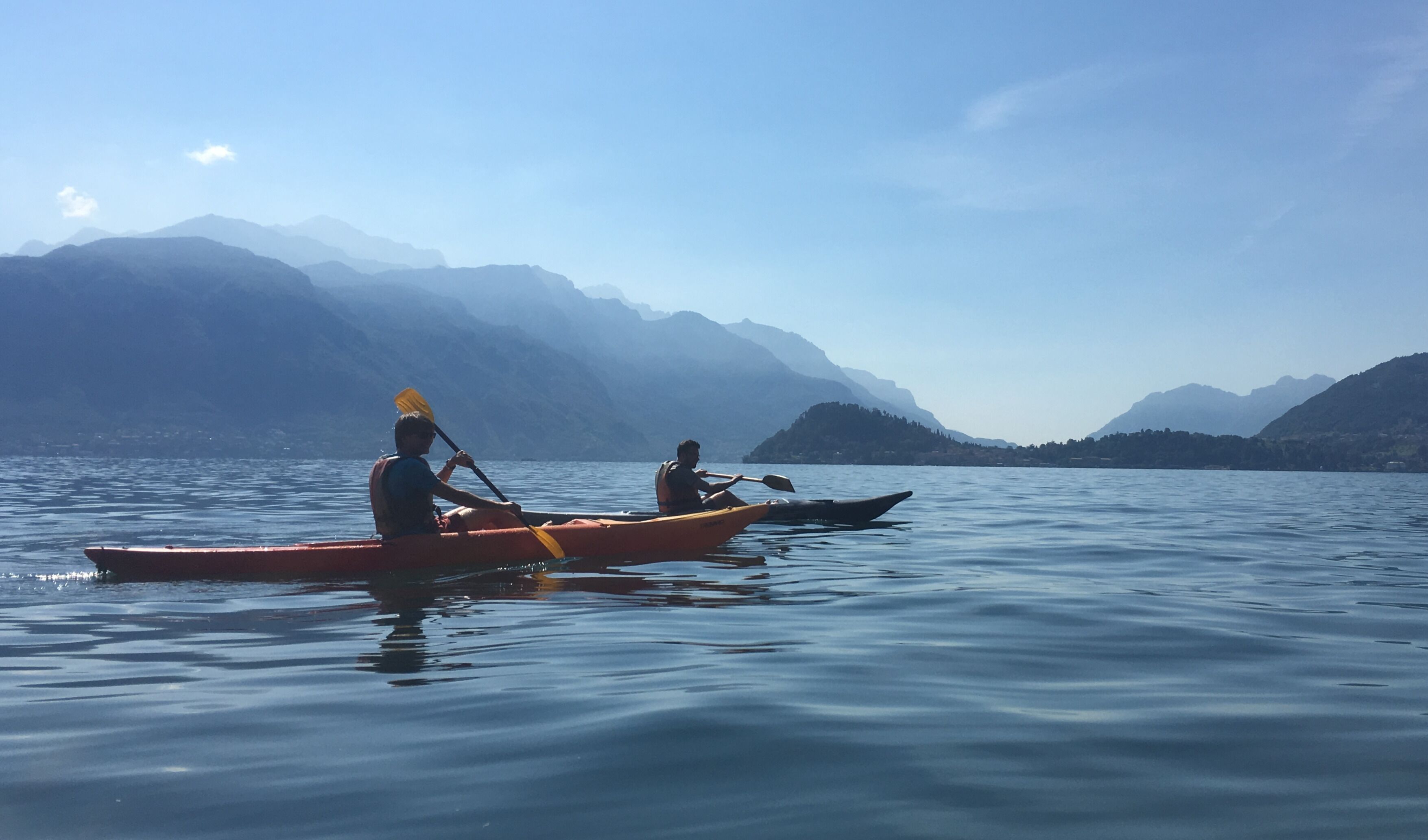Dos kayaks en aguas tranquilas, con montañas al fondo.