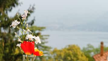 Eine Glasvase mit Blumen auf einem Balkon mit Blick auf einen See.