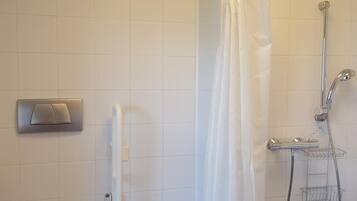 Un baño con inodoro, ducha con cortina y un perchero para toallas.