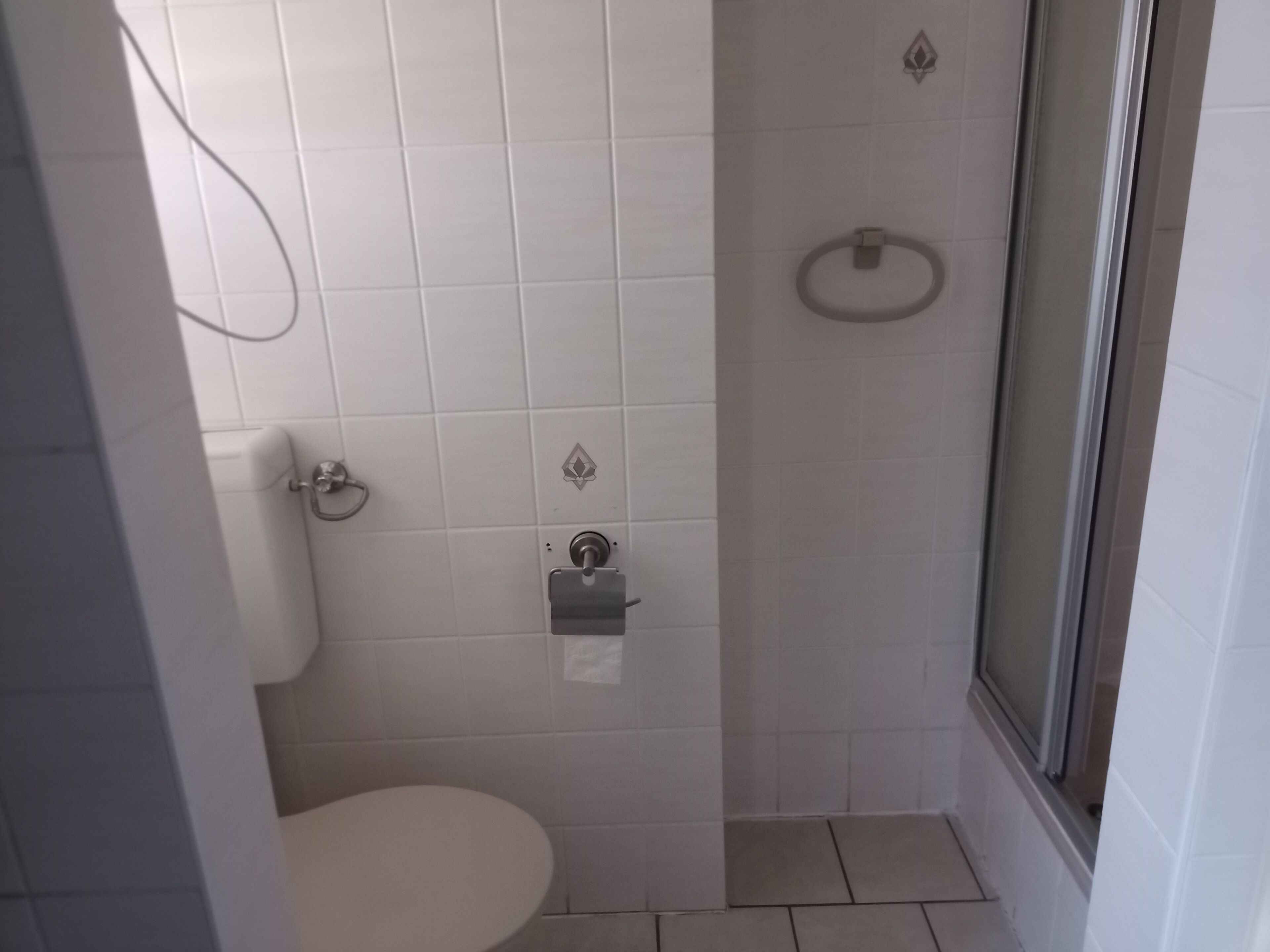 A small, modern bathroom with a toilet, a shower, and a glass door.