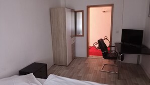A hotel room with a bed, a desk with a chair, a wardrobe, and a television. - Hotel zur Tanne (Zwickau)