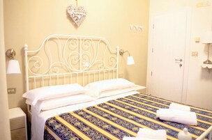 Un letto rifatto con cura, con una coperta a motivi decorativi, una testata bianca e una lampada da comodino.