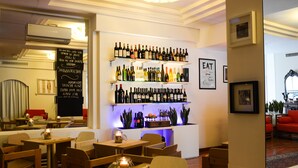 A restaurant with wooden tables and chairs, a bar area with wine bottles, and a chalkboard menu.