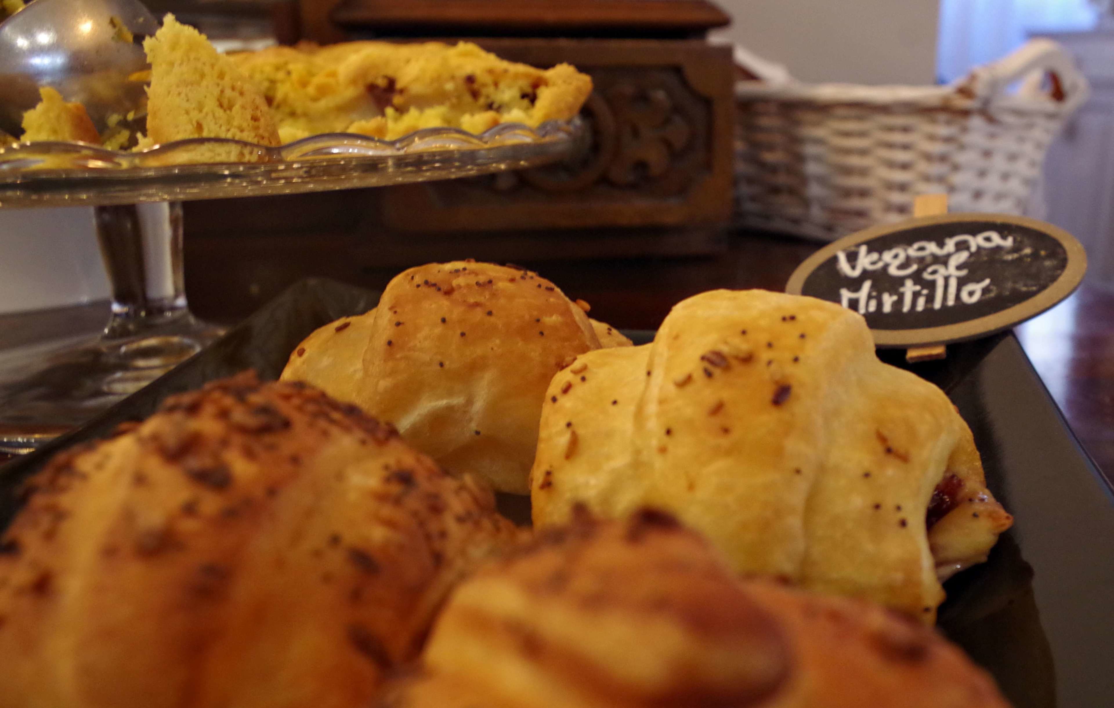 A tray of baked goods, including a piece of pie and several pastries, with a sign reading "Vegana de Murtilla".