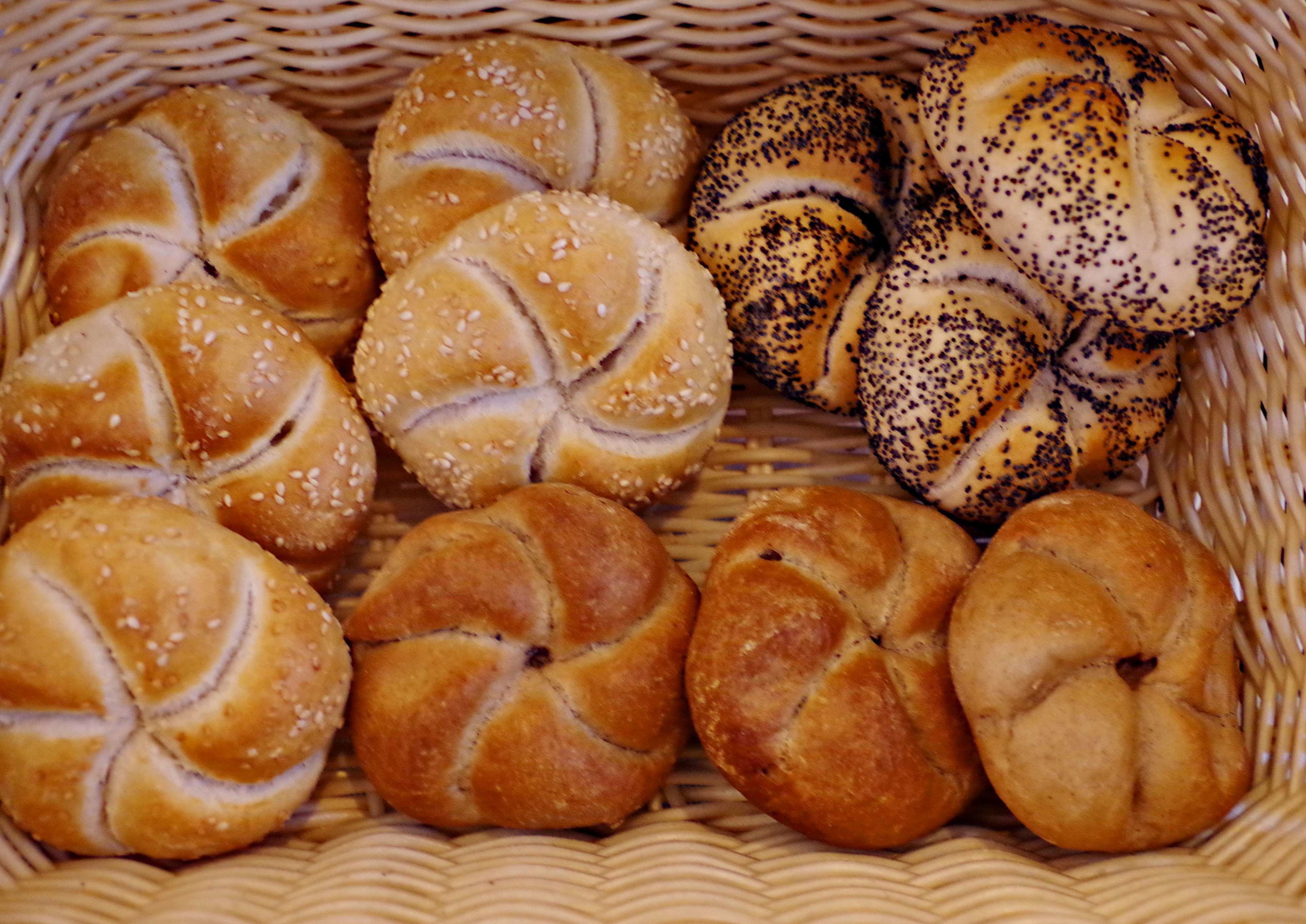 Un cesto con diversi tipi di pane, tra cui panini al sesamo e ai papaveri.