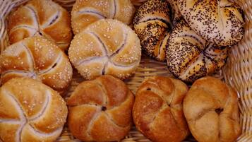Un cesto con diversi tipi di pane, tra cui panini al sesamo e ai papaveri.