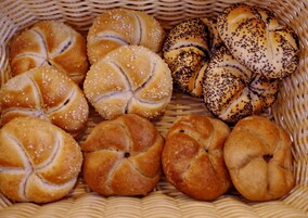 Un cesto con diversi tipi di pane, tra cui panini al sesamo e ai papaveri.