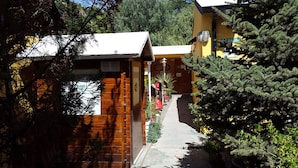 A narrow pathway leading to a wooden building with a sign indicating a regional office. - Apart El Nevado (Malargüe)