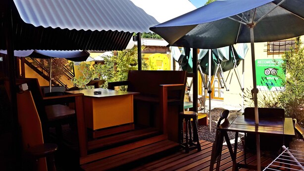 An outdoor seating area with wooden furniture, umbrellas, and a view of the surrounding buildings. - Apart El Nevado (Malargüe)
