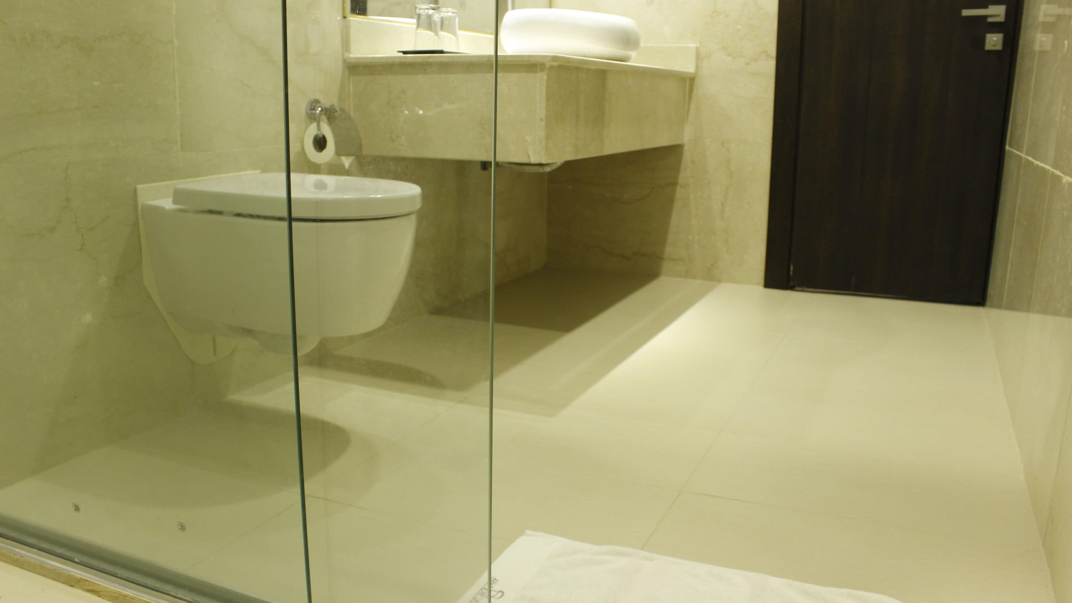 A modern bathroom with a glass-enclosed shower, a white toilet, and a marble sink.