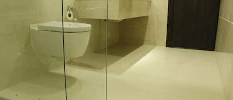 A modern bathroom with a glass-enclosed shower, a white toilet, and a marble sink.
