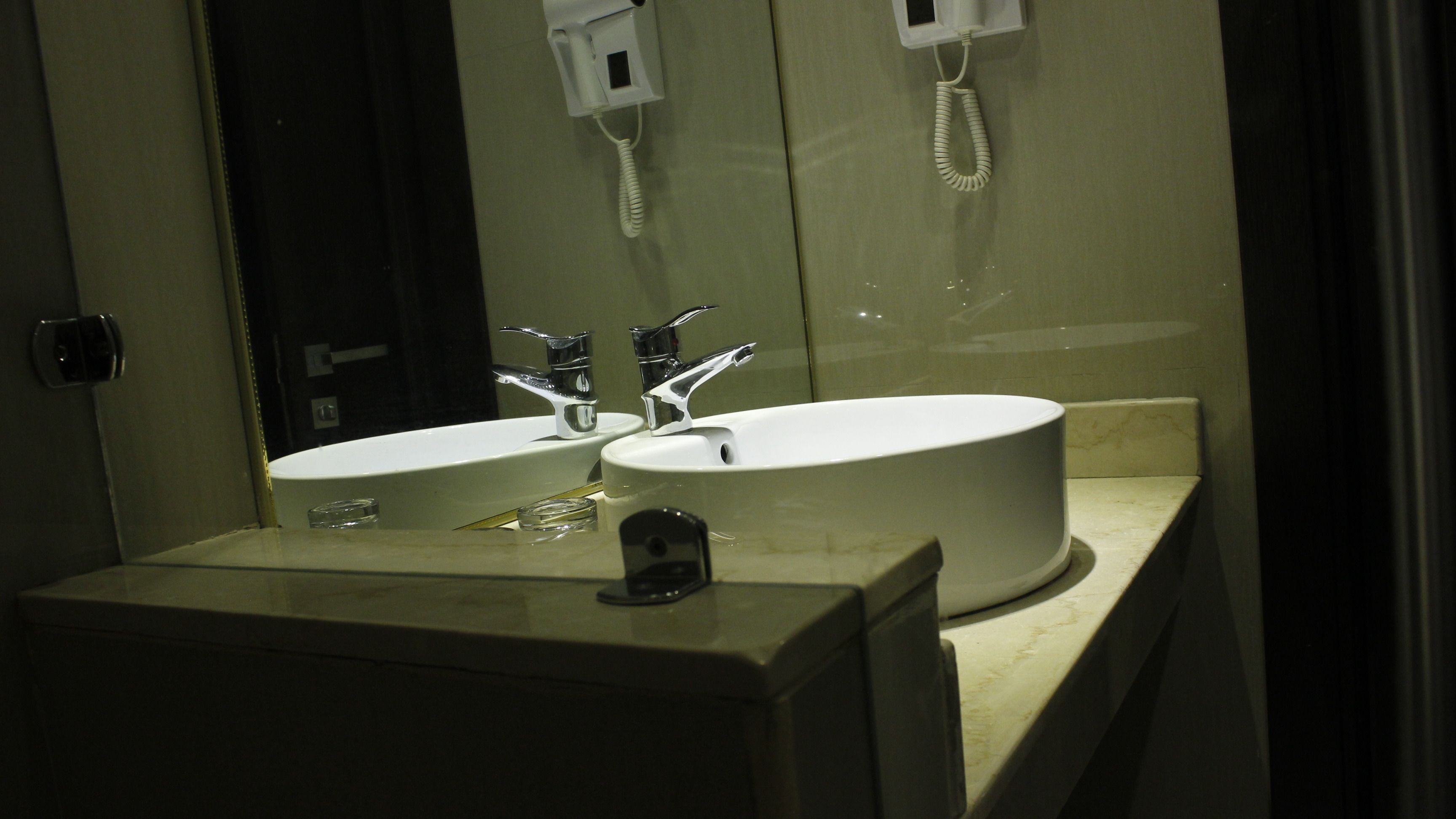 A bathroom with two sinks, a mirror, and a telephone.