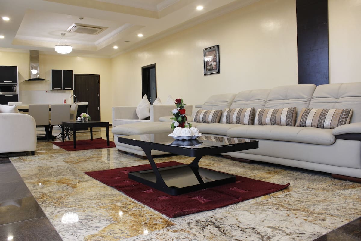 A modern living room with a sofa, a coffee table, and a kitchen in the background.