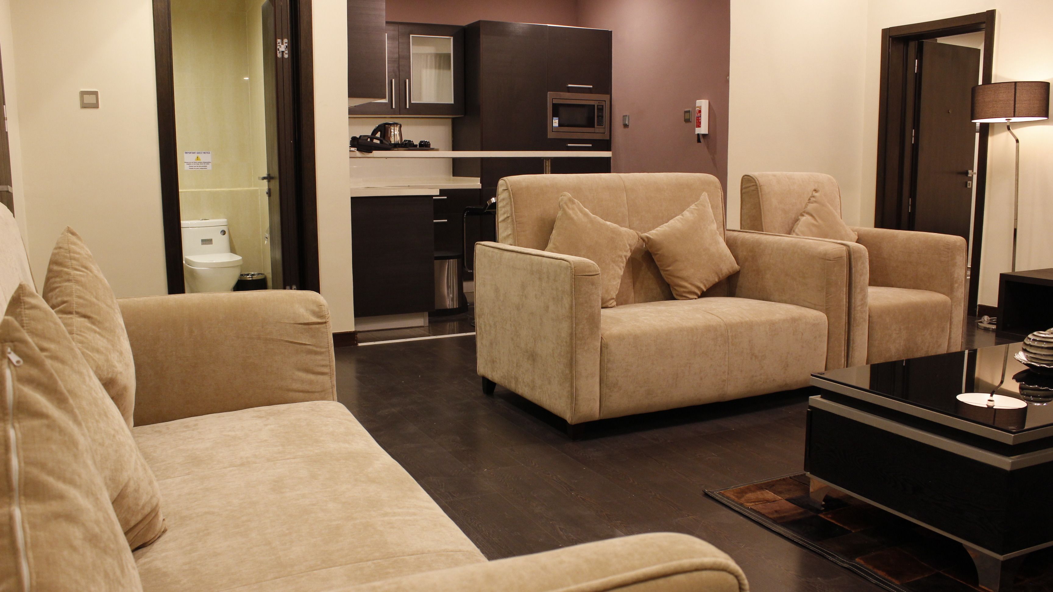 A modern living room with a sofa, two armchairs, a coffee table, and a flat-screen TV.