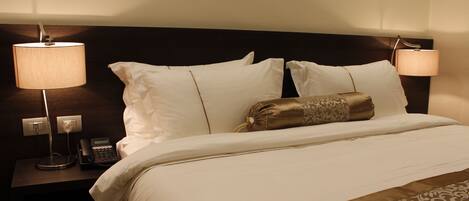 A hotel room with a neatly made bed, two bedside lamps, a bedside phone, and a nightstand.