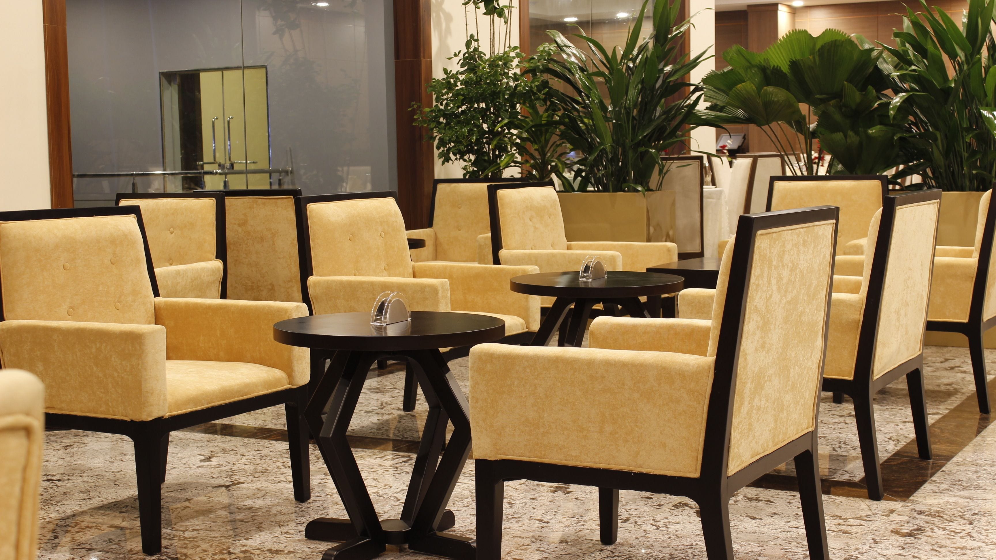 A seating area with yellow upholstered chairs and black tables, arranged in a semi-circular pattern.
