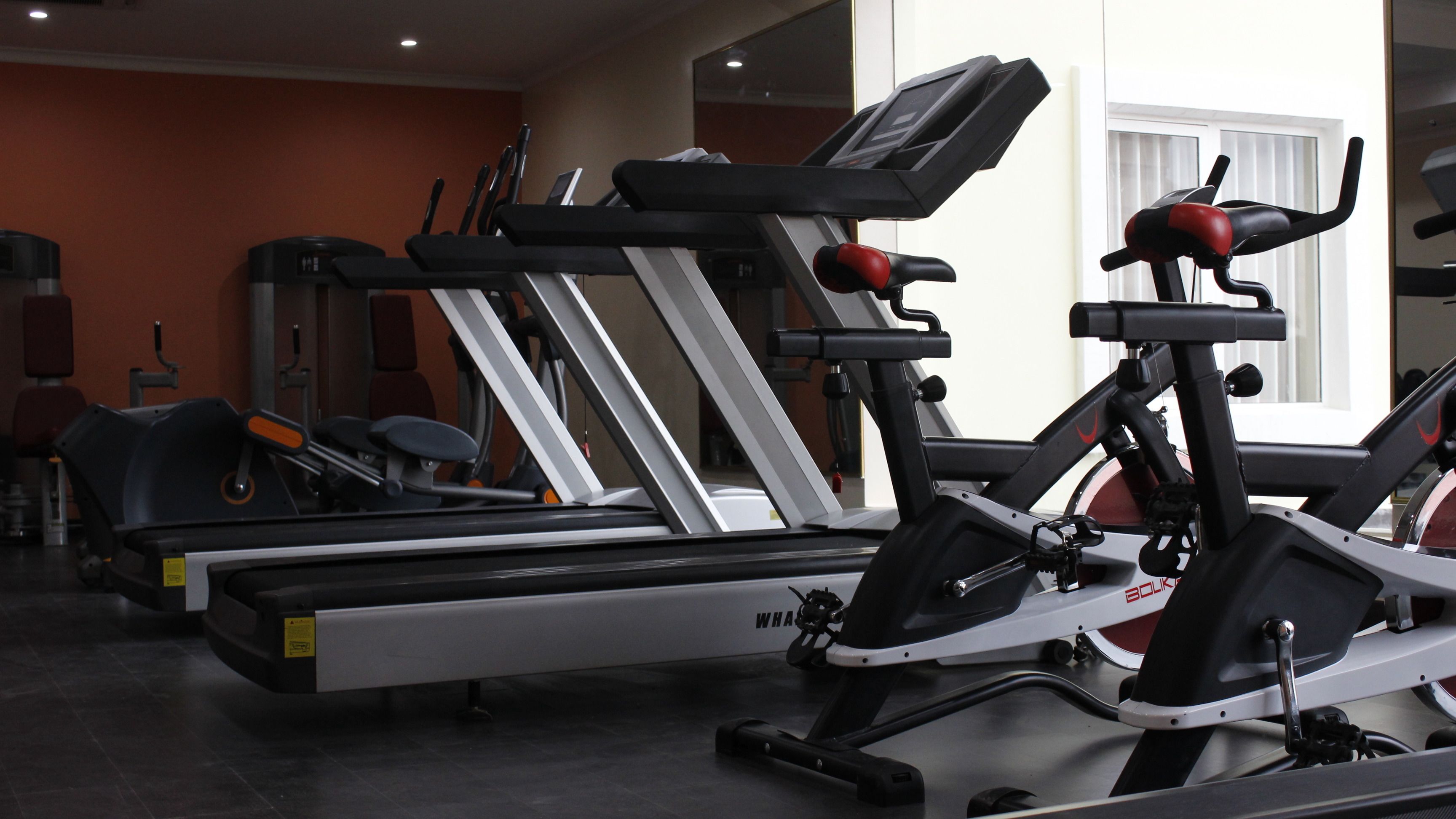 Une salle de sport équipée de divers appareils d’exercice, notamment des tapis de course et des vélos d’appartement.