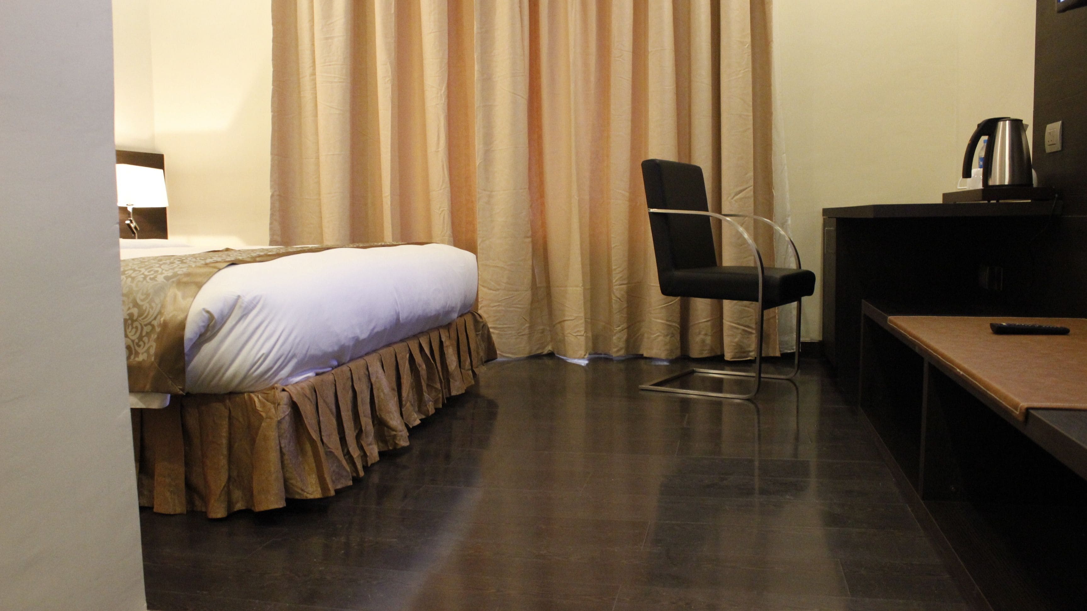 Una habitación de hotel con cama, sillón, escritorio y tetera.