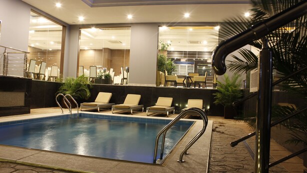 Piscina com espreguiçadeiras e área de recepção.