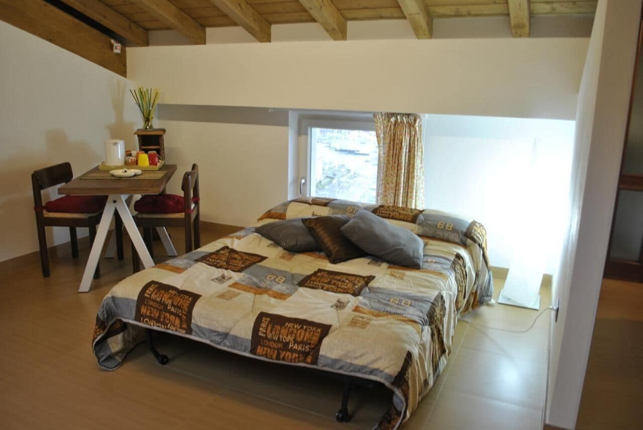 A bedroom with a bed, a desk, and a window.