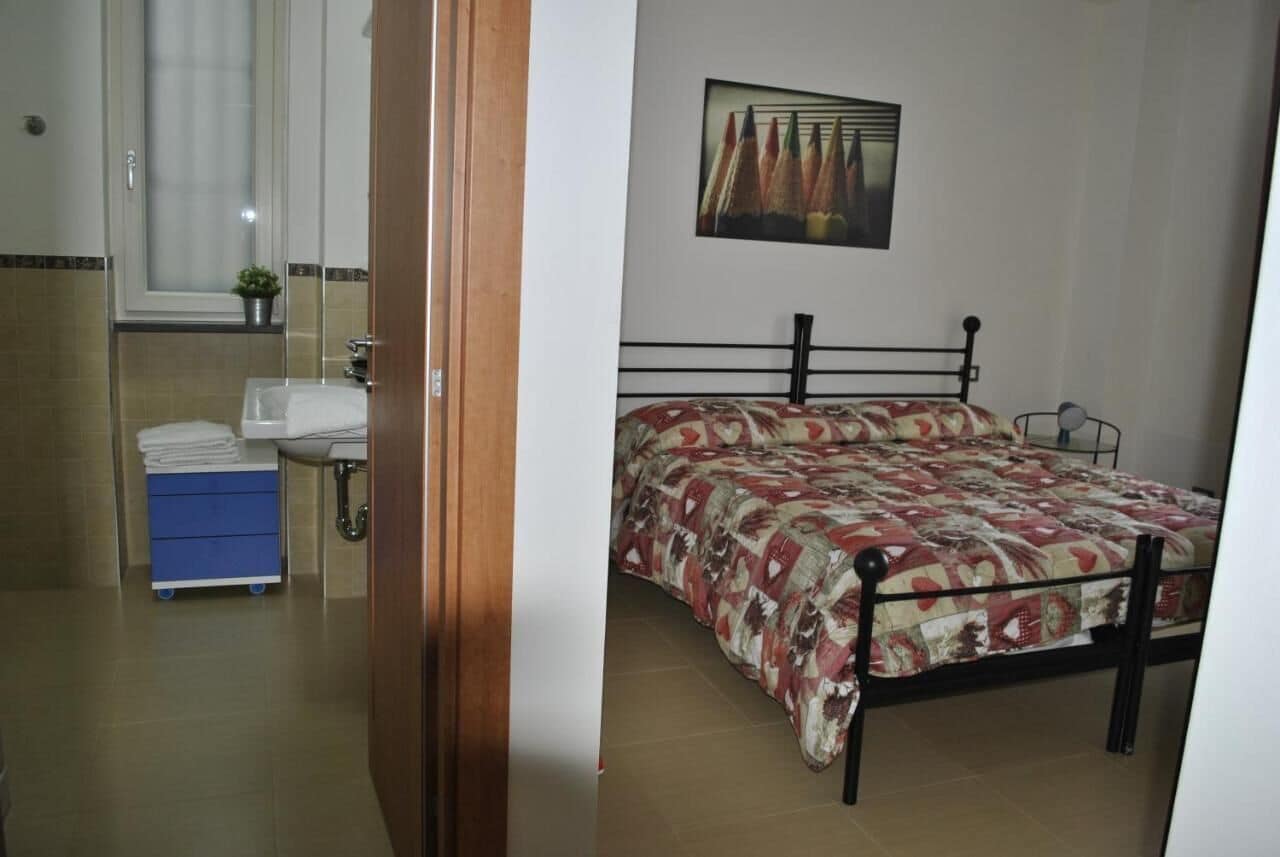 A bedroom with a bed, a window, a sink, and a blue cabinet.