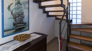 A wooden staircase with a modern design, a framed ship painting on the wall, and a decorative bowl on a wooden console table. - La Finestra sul Golfo Affittacamere (La Spezia)