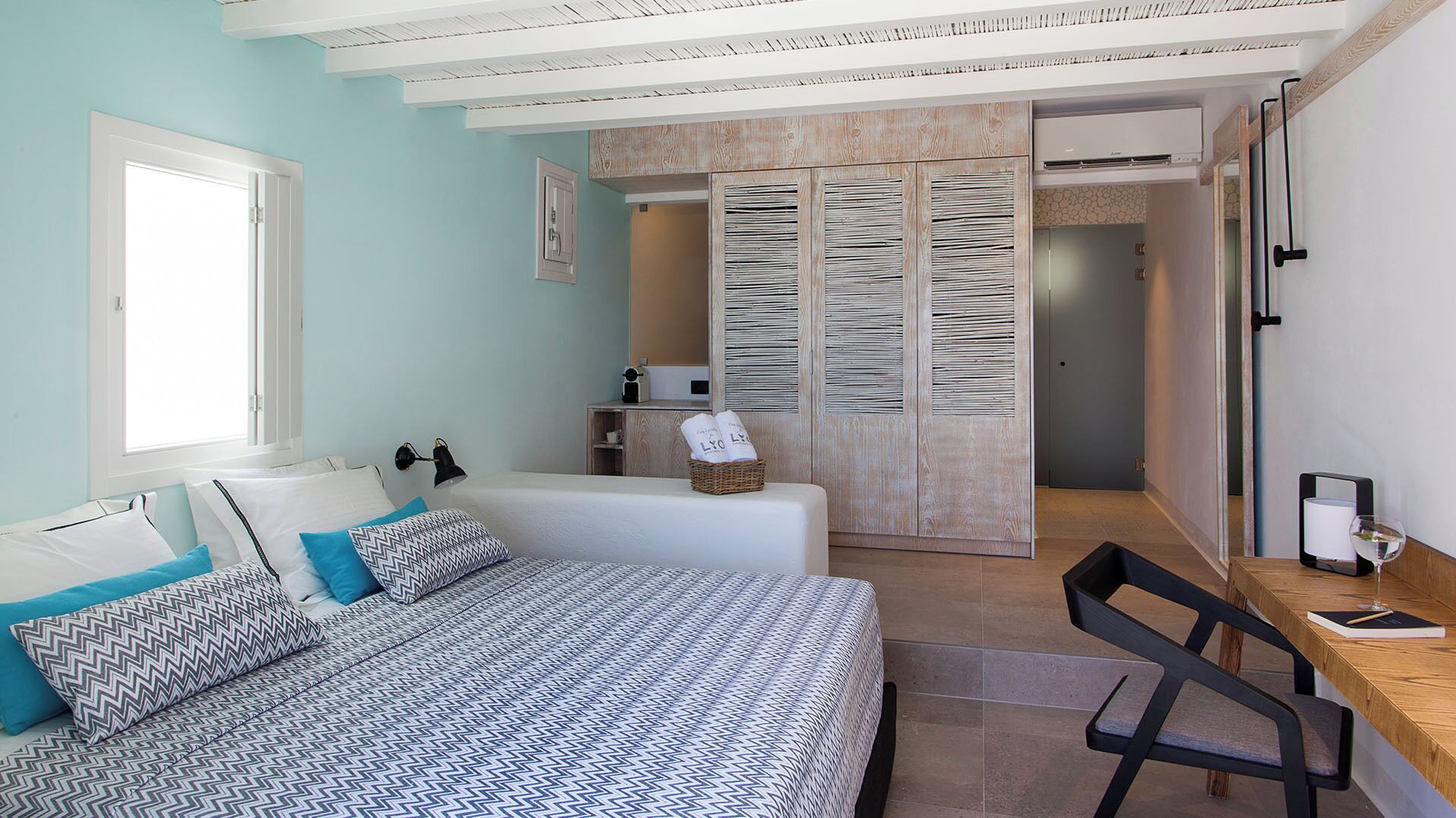 A bedroom with a bed, a desk, and a wardrobe.