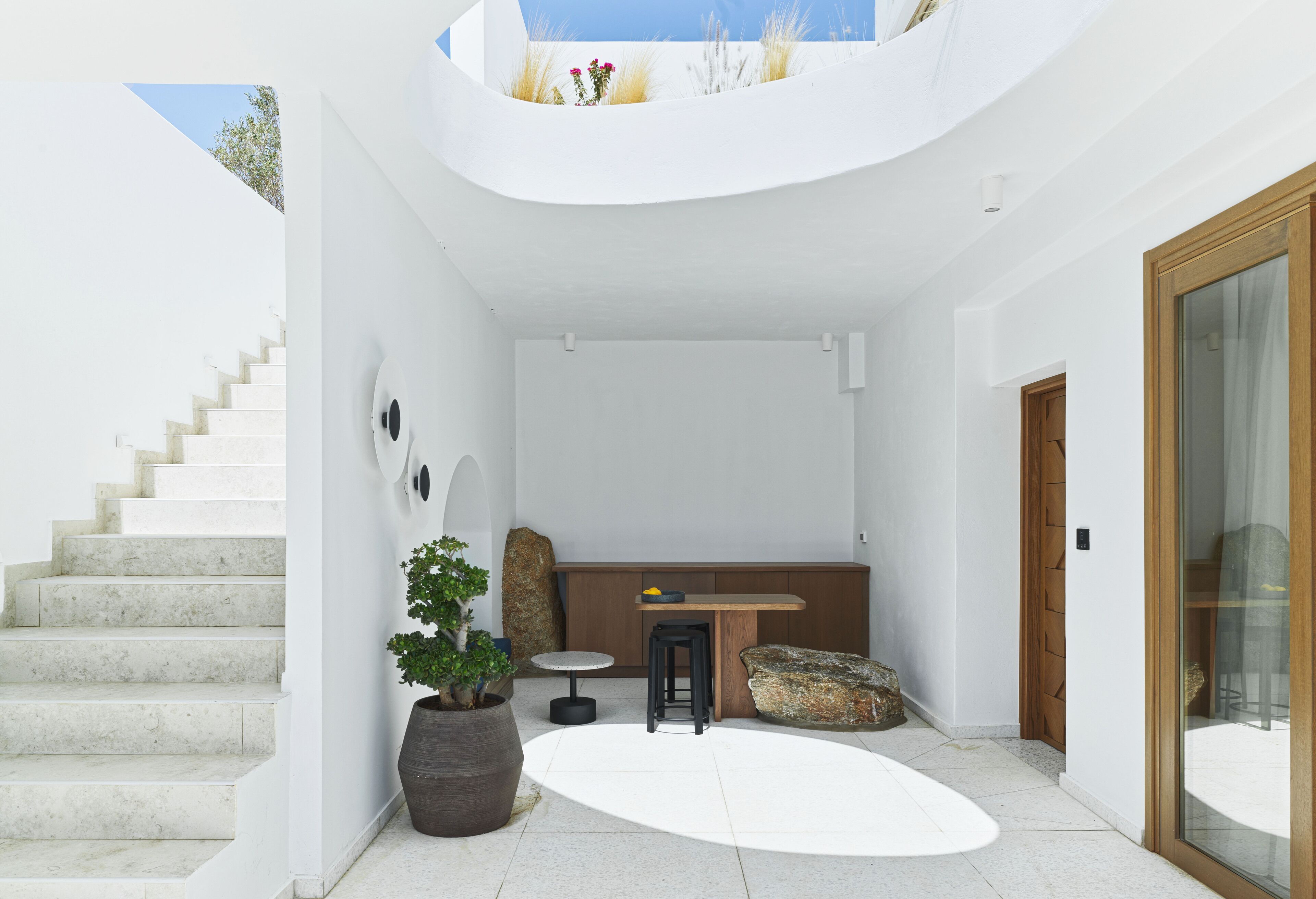 A modern interior with a staircase, a seating area, and a dining space.