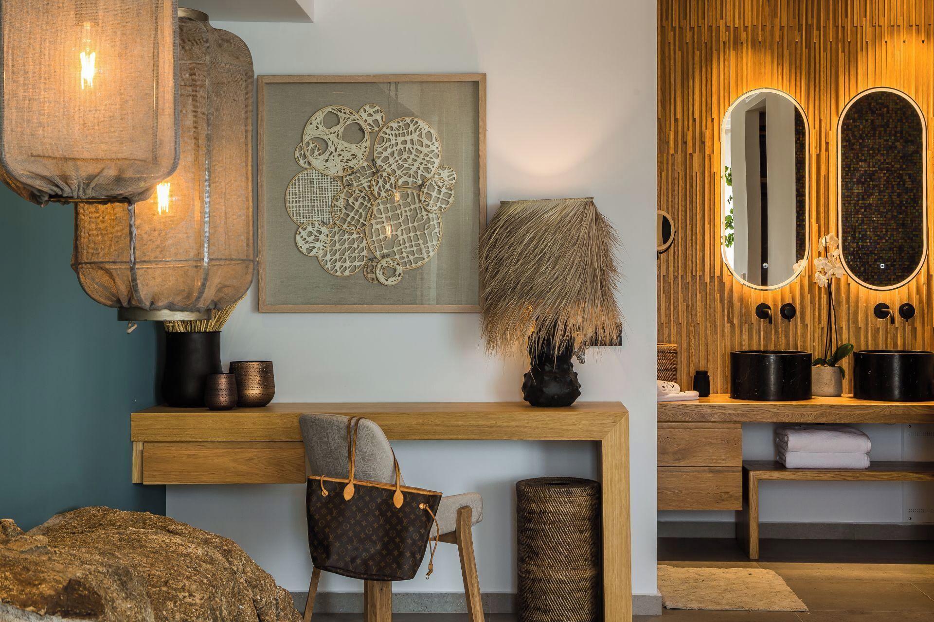 A modern bathroom with a wooden vanity, a large mirror, and a decorative wall piece.