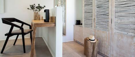 A modern room with a wooden desk, a black chair, a small wooden stool, and a woven basket with plants.