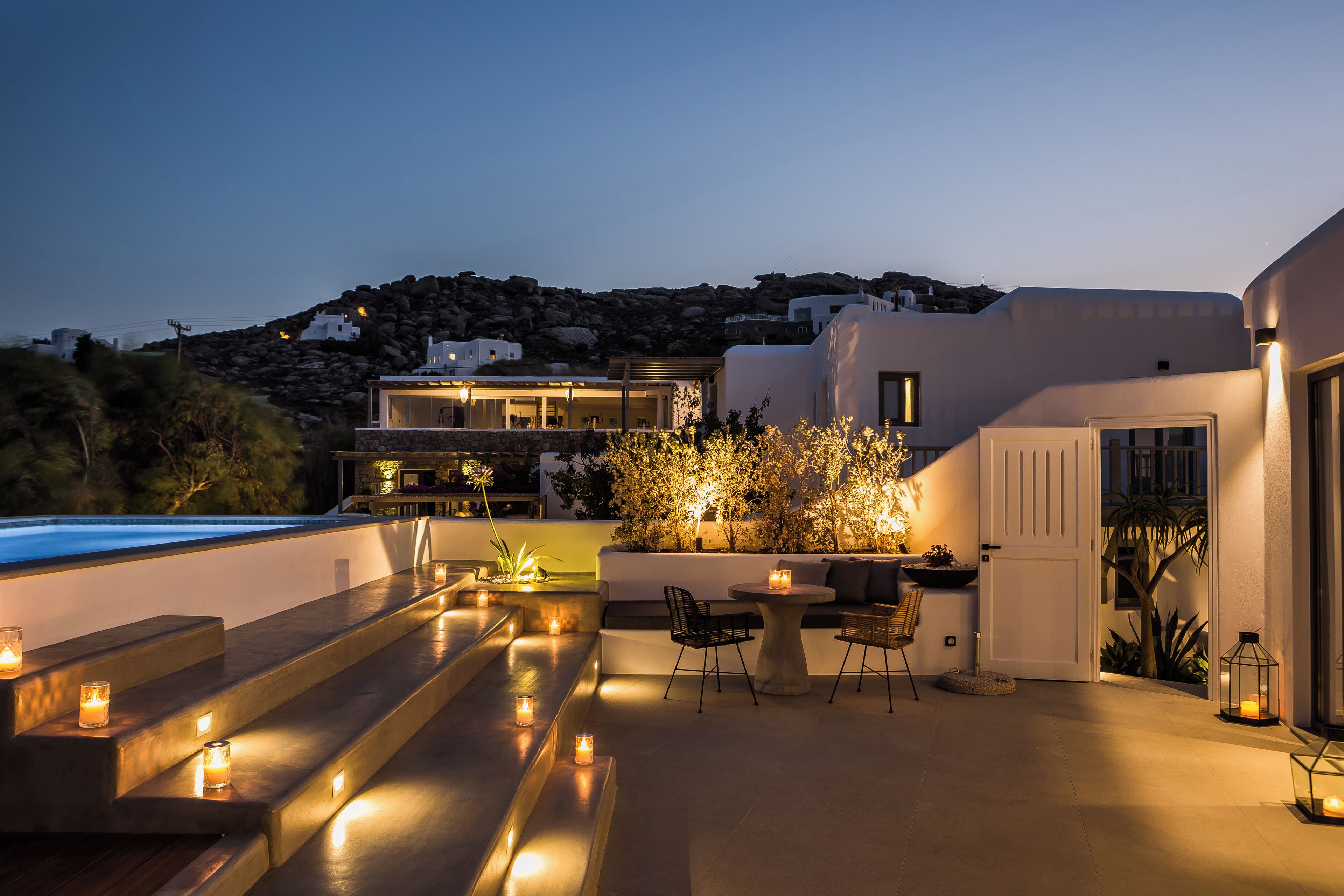 Una terraza en la azotea con mobiliario, una piscina y vistas del paisaje circundante.
