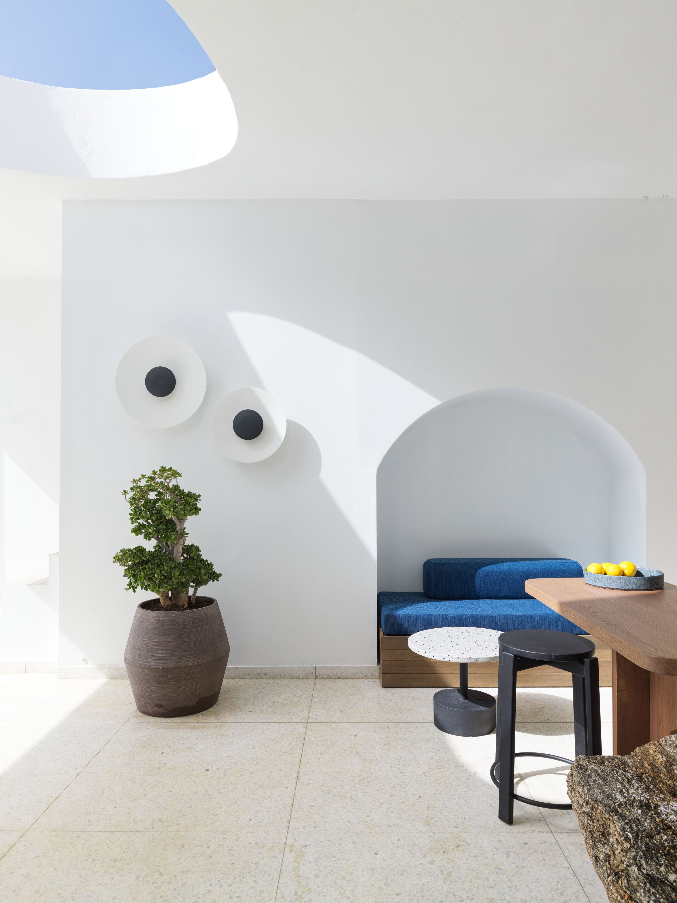 A modern interior with a blue sofa, a round table, and a potted plant.