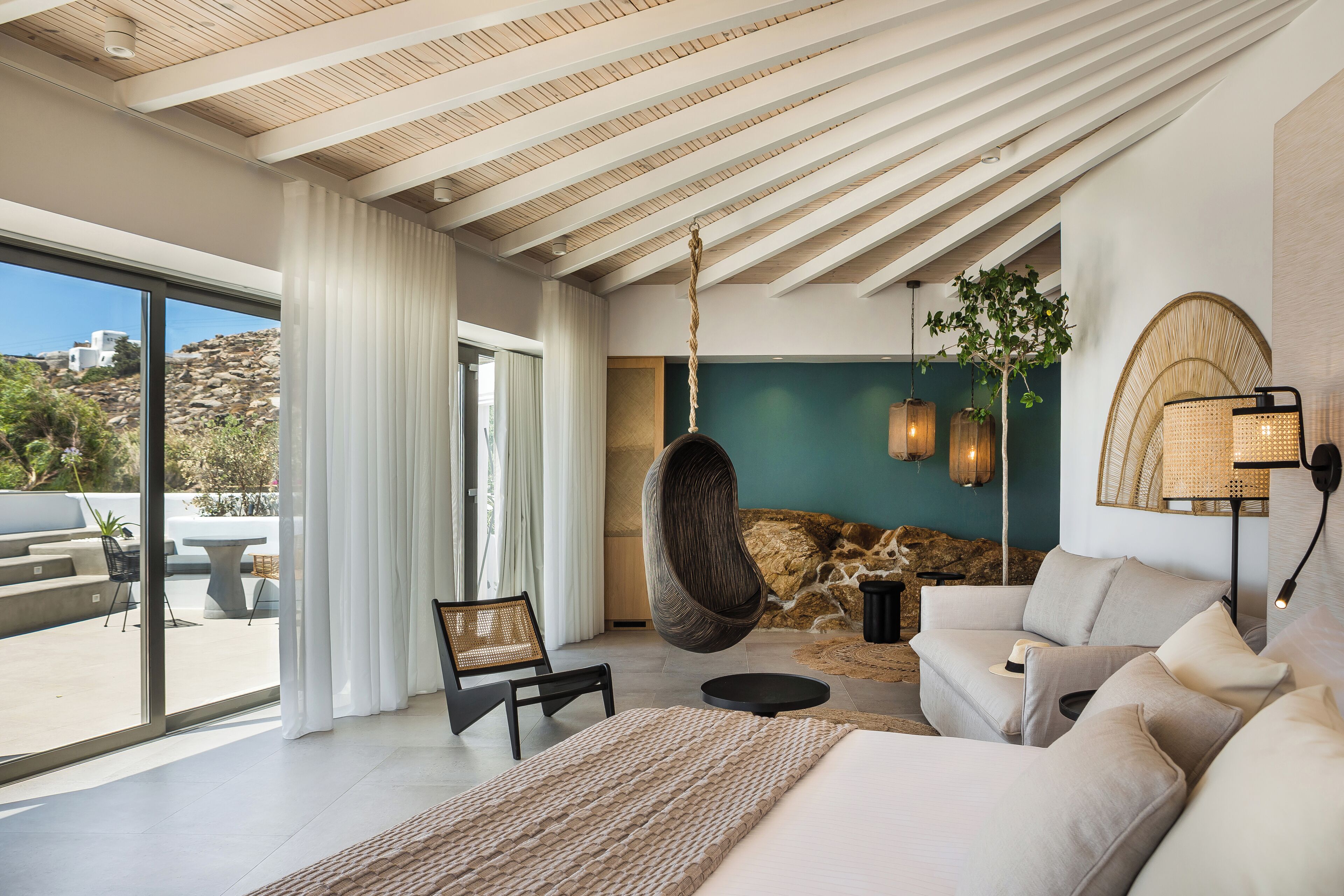 Un interior moderno con una silla colgante, un sofá y un ventanal con vistas al exterior.