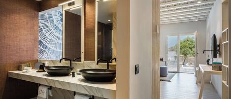 A modern bathroom with two sinks, a large mirror, and a view of the outdoor area.