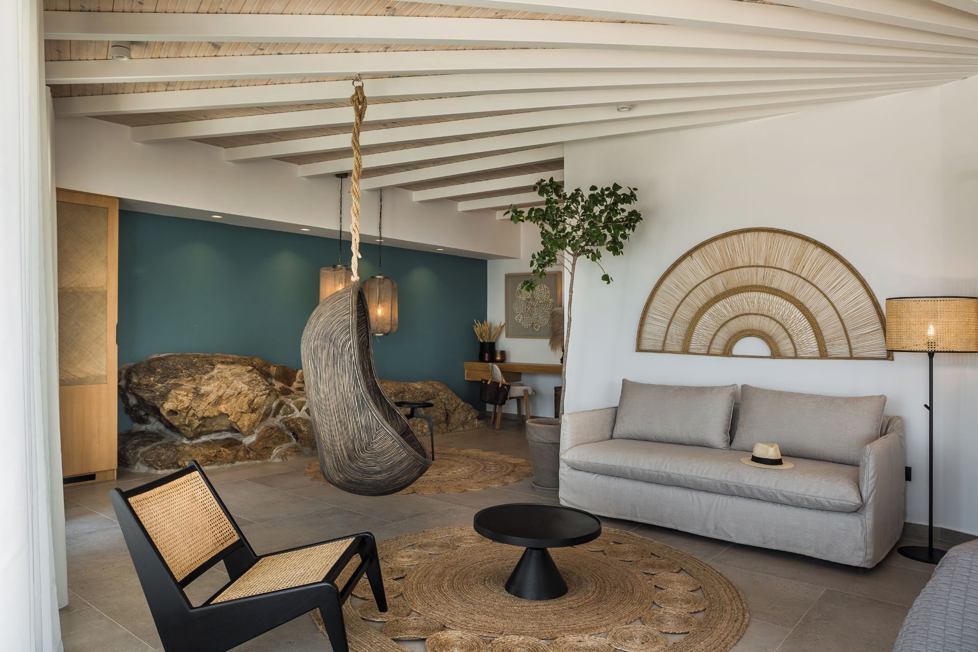 A modern living room with a hanging chair, a sofa, a coffee table, and a lamp.